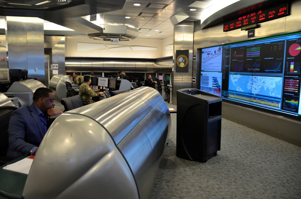 People sit and work at large metal desks at U.S. Army Cyber Command headquarters