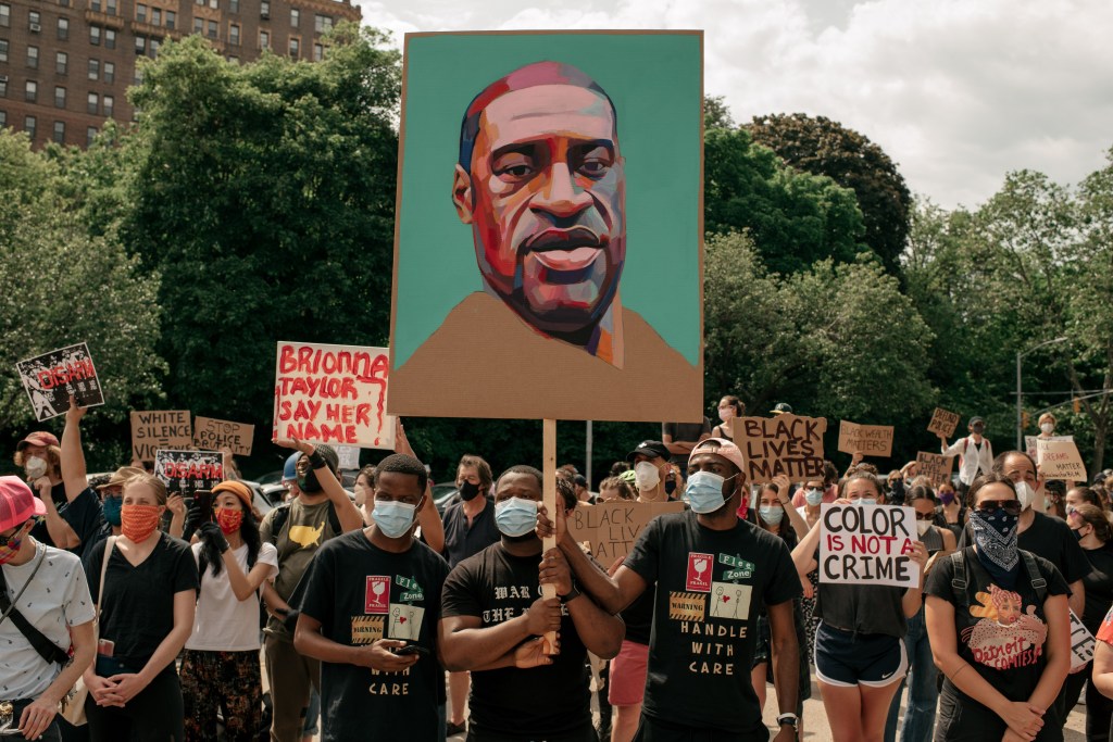 A Black Lives Matter protest on June 4, 2020 in New York City. Demonstrators hold signs, one is a large picture of George Floyd, who was killed by police on May 25th. Other signs read, “Black Lives Matter,” “Color is not a crime,” “Brionna Taylor Say Her Name,” White Silence Equals Violence,” and “Stop Police Brutality.” Demonstrators wear face masks due to the coronavirus.