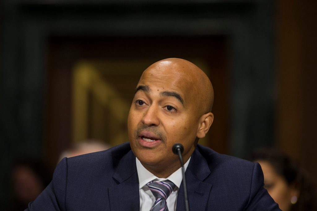 photograph of Travis LeBlanc speaking into a microphone.