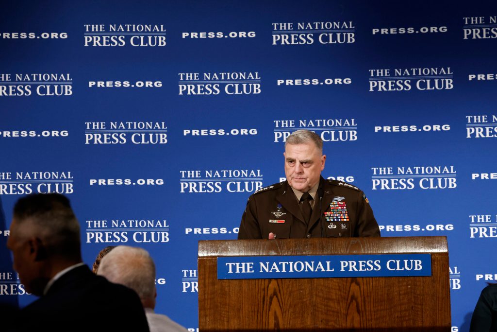 U.S. Joint Chiefs of Staff Chairman Gen. Mark Milley stands at a podium in uniform behind blue background with the words "National Press Club" written in white text.