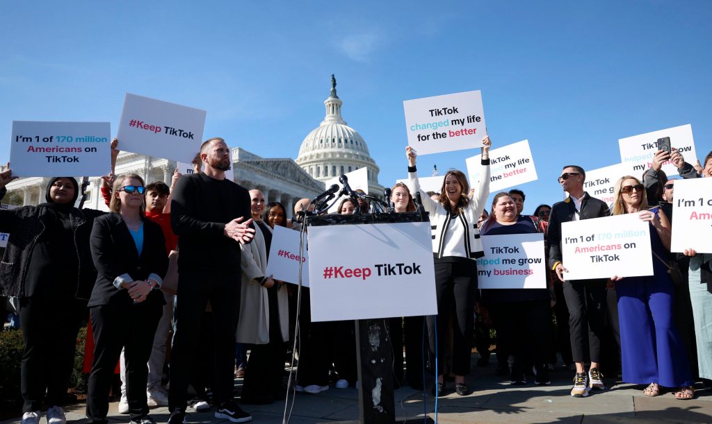 Participants hold up signs in support of TikTok