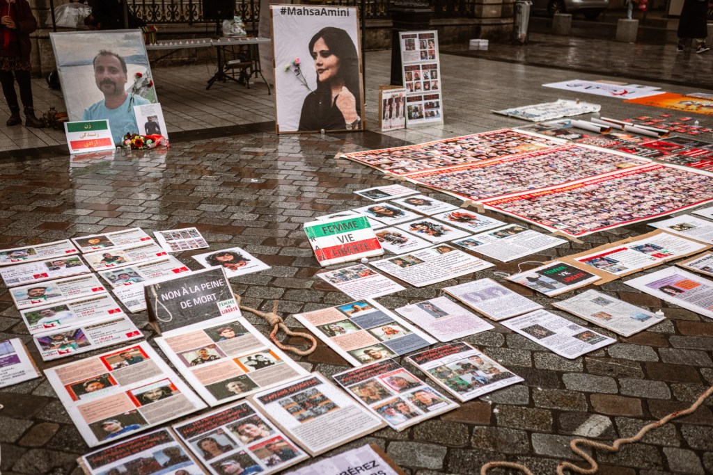 Posters are displayed on the ground during a rally in support of the Iranian people and the Women Life Freedom movement
