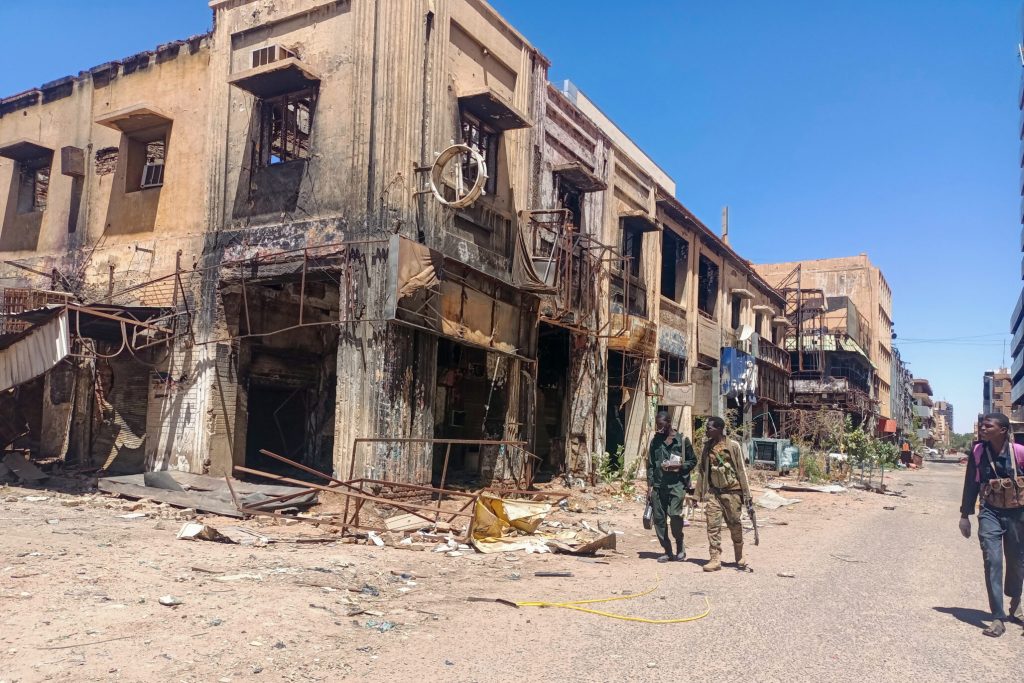 Two soldiers walk past a destroyed building in Khartoum.