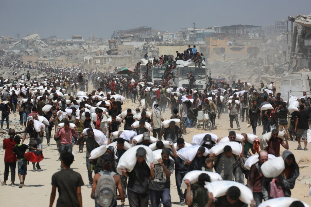 Palestinians walk carrying sacks of flour