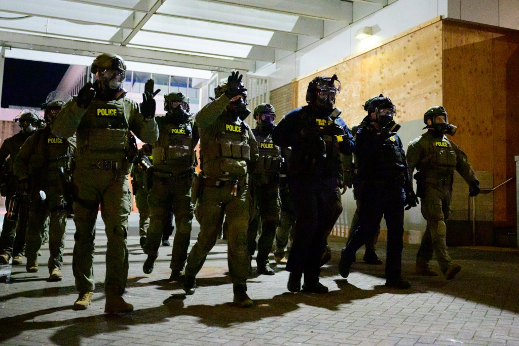 Federal agents keep protestors back from an Immigration and Customs Enforcement (ICE) facility