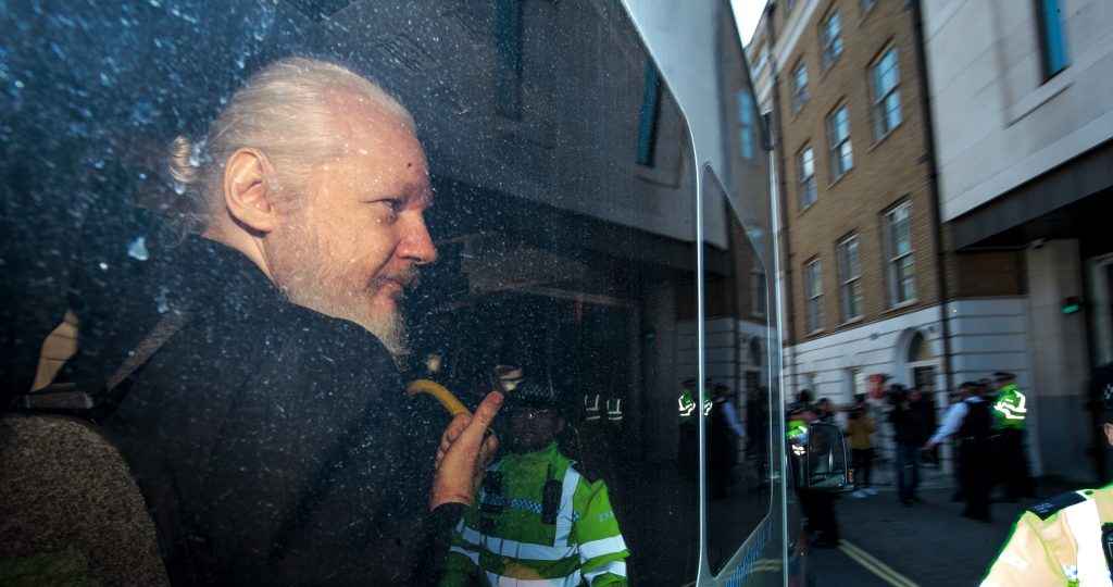 Julian Assange gestures to the media from a police vehicle on his arrival at Westminster Magistrates court on April 11, 2019 in London, England.