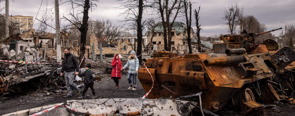 Residents walk amid debris and destroyed Russian military vehicles on a street on April 06, 2022 in Bucha, Ukraine. The Ukrainian government has accused Russian forces of committing a "deliberate massacre" as they occupied and eventually retreated from Bucha, 25km northwest of Kyiv. Hundreds of bodies were found in the days after Ukrainian forces regained control of the town. (Photo by Chris McGrath/Getty Images)